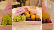fresh fruit basket with mangoes, grapes, and plums wrapped in pink tulle