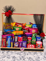 Load image into Gallery viewer, Large snack hamper filled with chips, chocolate bars, candies and drinks, decorated with red roses and black netting.