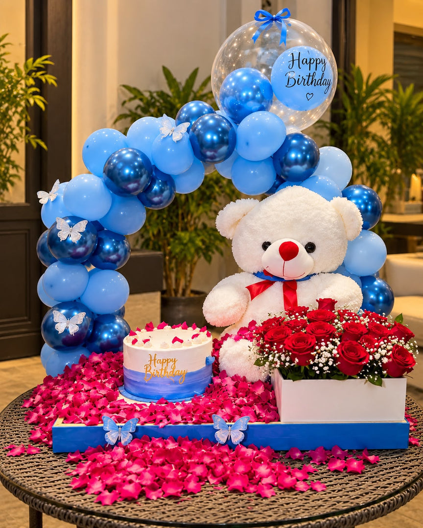 Aqua Reverie luxury birthday setup with blue balloons, teddy bear, red roses and cake