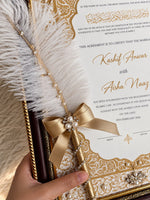 Load image into Gallery viewer, Personalised gold and ivory Nikah certificate in an ornate frame with Arabic calligraphy, custom couple names, pearl embellishments, and a feather-decorated pen.