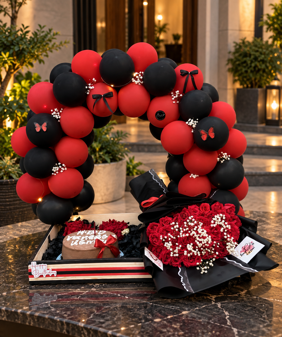 Elegant Crimson Noir birthday surprise with red flowers and decorative balloon arch