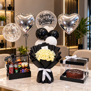 Midnight Monochrome luxury birthday gift set with white roses, silver heart balloons, cake box and snack hamper
