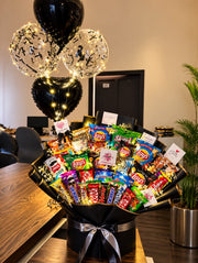 Luxury chocolate and snacks bouquet with assorted chocolates, chips, black wrapping, silver ribbon and decorative balloons