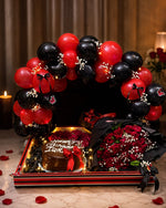Load image into Gallery viewer, Rouge Eclipse red and black celebration setup with balloon arch, red roses, chocolate cake and fairy lights