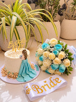 Load image into Gallery viewer, Ivory bridal shower cake with a turquoise gown decoration and gold Bride to Be topper beside an ivory and turquoise rose bouquet and Bride sash.

