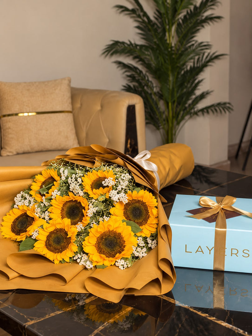 Yellow sunflower bouquet wrapped in golden paper paired with a Milky Malt Cake gift.