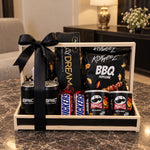 Load image into Gallery viewer, Wooden snack gift hamper with black ribbon, chocolates, popcorn, chips, and drinks arranged in a premium gift crate.