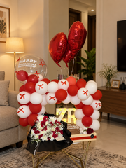 Scarlet Promise engagement celebration setup with red and white balloon arch, heart balloons, roses and personalized cake