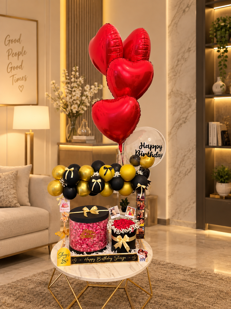 Black and gold birthday setup with red heart balloons and roses