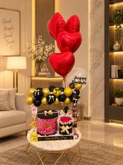 Black and gold birthday setup with red heart balloons and roses