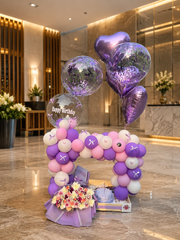 Lilac Whimsy birthday setup with pink purple and white balloon arch and flower bouquet