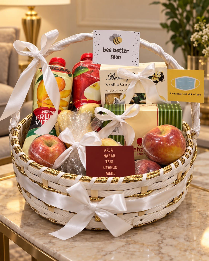 Get-well-soon gift hamper in a white woven basket with fruit drinks, fresh apples, biscuits, satin ribbons, and greeting cards.