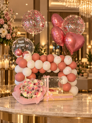 Rose pink balloon arch with heart foil balloons, pink bouquet and birthday cake in a clear box