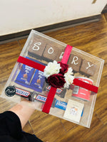 Load image into Gallery viewer, Sorry treat box with chocolate brownies, assorted chocolates, snacks, flowers, and an apology card in a transparent gift box
