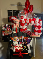 Load image into Gallery viewer, Premium anniversary gift arrangement featuring Ferrero Rocher chocolates, snack bouquet, teddy bear, fresh roses, and romantic balloon decoration