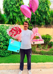 Luxury gift set featuring a rose bouquet, assorted chocolate gift basket, decorative balloons, and elegant gift bag for birthdays and anniversaries
