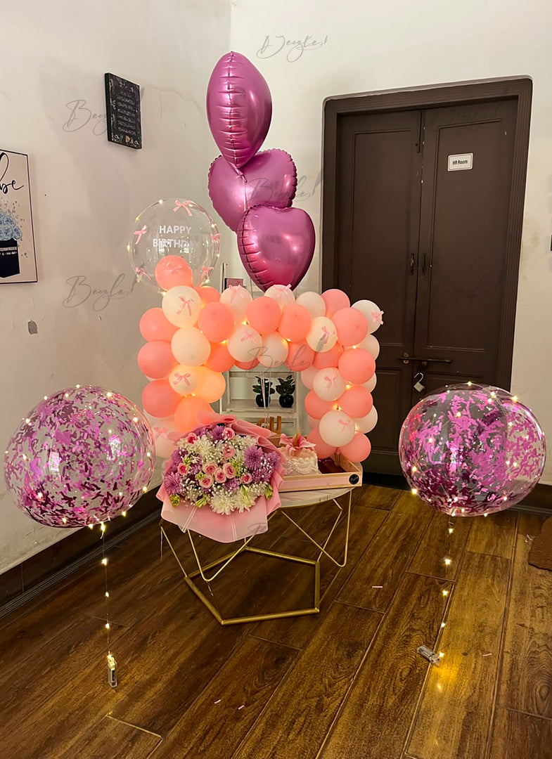 Pink floral gift ensemble with chocolates, cake and layered balloons