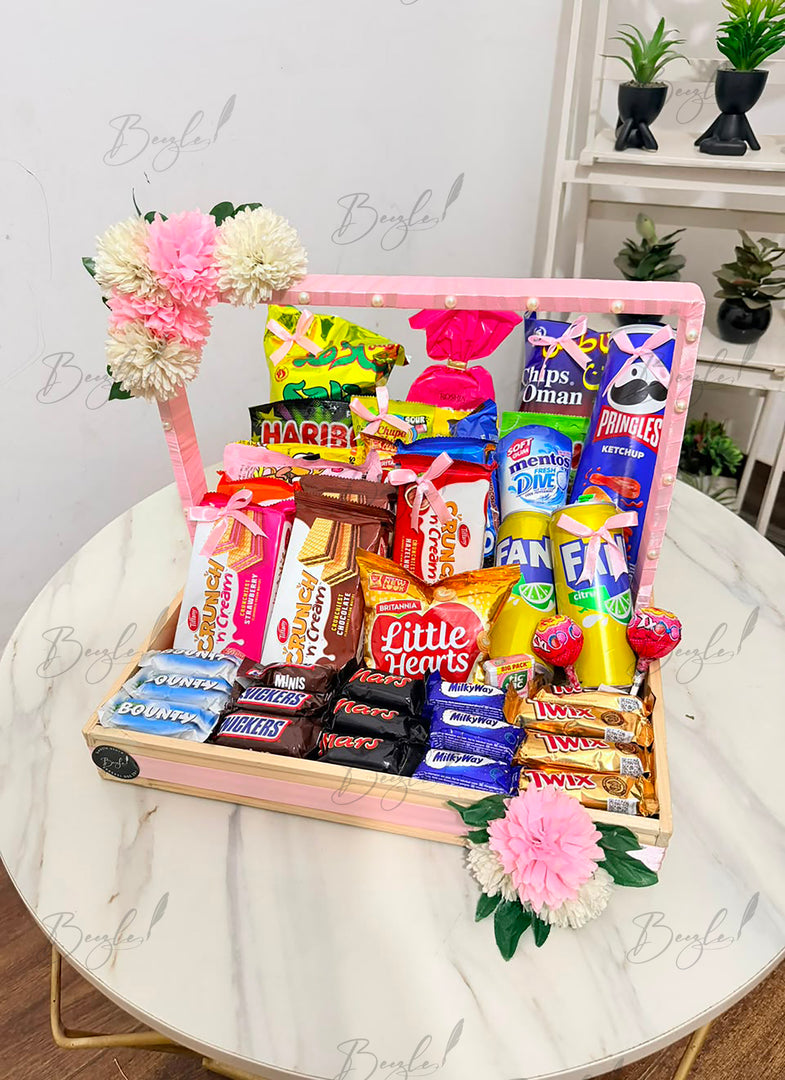 Colorful snack and chocolate gift basket with pink and white flowers
