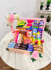 Colorful snack and chocolate gift basket with pink and white flowers