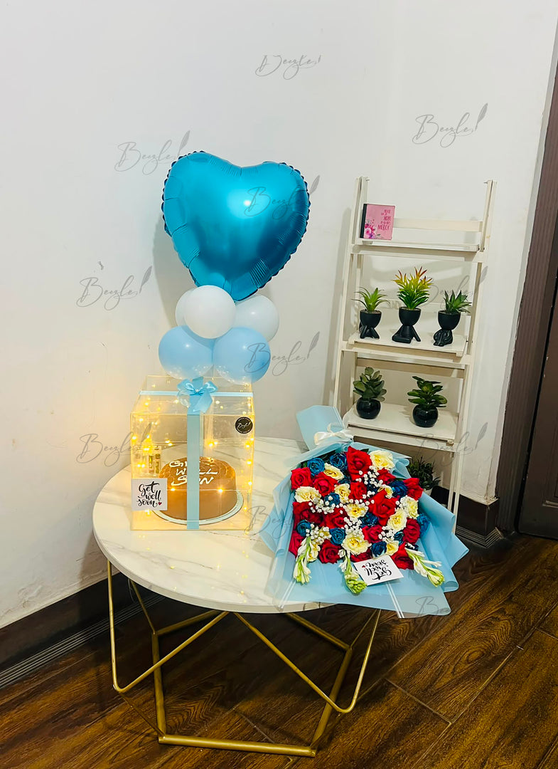Elegant celebration gift arrangement with blue balloon, fresh flowers, and decorative light-up box.