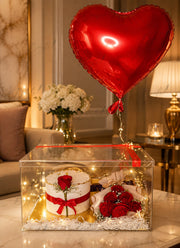 The Grand Gesture luxury gift set with red roses, white cake, heart balloon, fairy lights, and transparent acrylic display box.