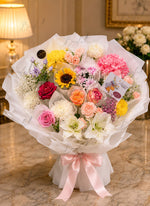 Load image into Gallery viewer, Rainbow Blossom Bouquet with colorful fresh flowers, roses, sunflower, hydrangea, elegant white wrapping, and pink ribbon.