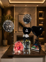 Midnight Royale luxury birthday setup with black balloons, glowing gift box, money bouquet, and snack hamper.