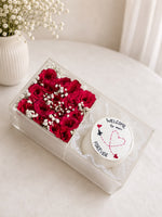 Load image into Gallery viewer, Clear acrylic gift box with deep red roses, white baby's breath, and a decorated white cake