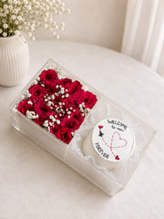 Clear acrylic gift box with deep red roses, white baby's breath, and a decorated white cake