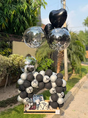 Noir Birthday Charm with black and silver balloon arch and gift box