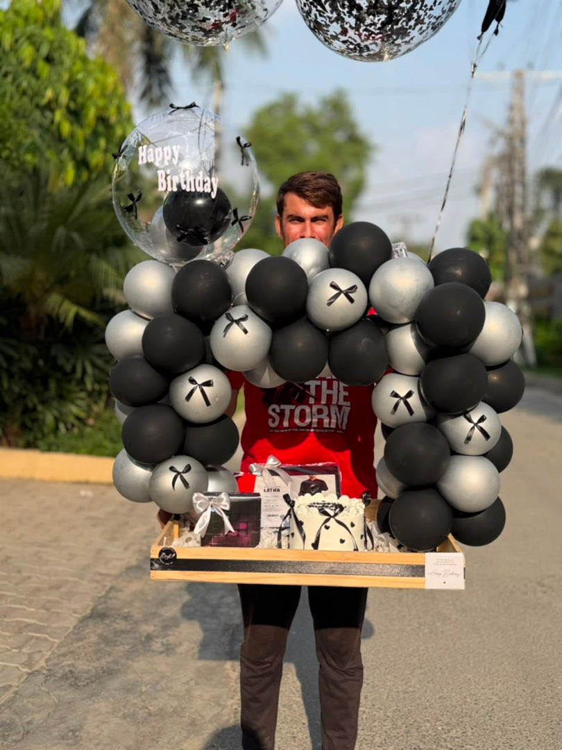 Black and white birthday gift setup with balloons and personalized cake