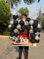 Black and white birthday gift setup with balloons and personalized cake