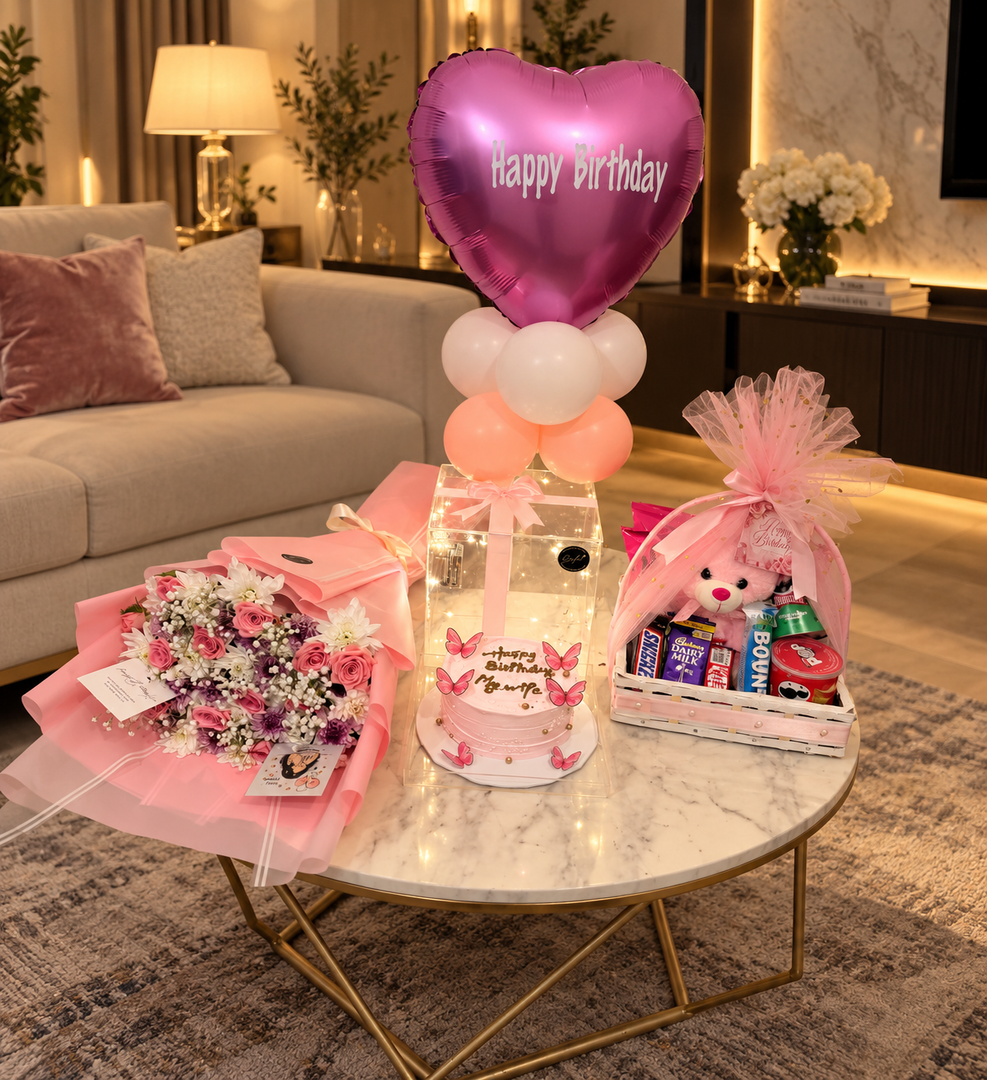 Pink birthday surprise featuring flowers, teddy bear gift basket, chocolates and decorative balloons