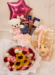 Aurum Curation luxury gift hamper with LED birthday cake box, teddy bear, chocolates, perfume, pink roses, red roses, sunflowers, and balloon