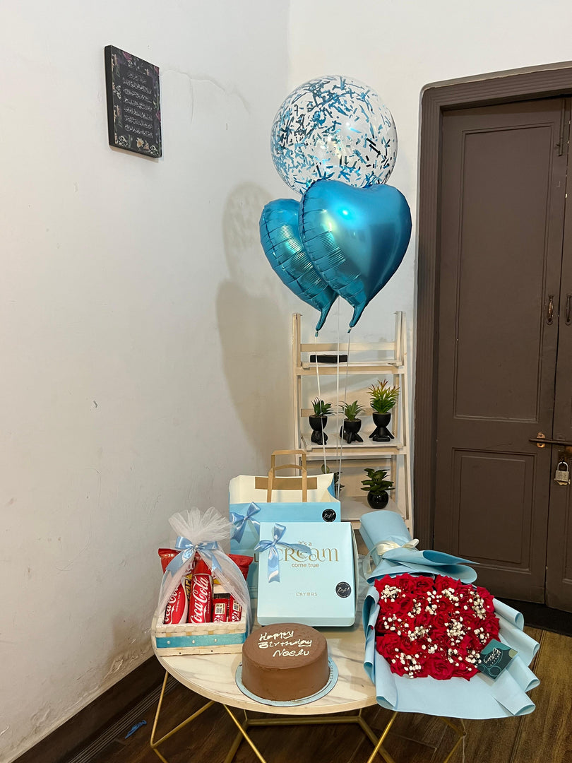 Ruby Birthday Luxe premium birthday gift arrangement with red roses, cake, treats and blue balloons