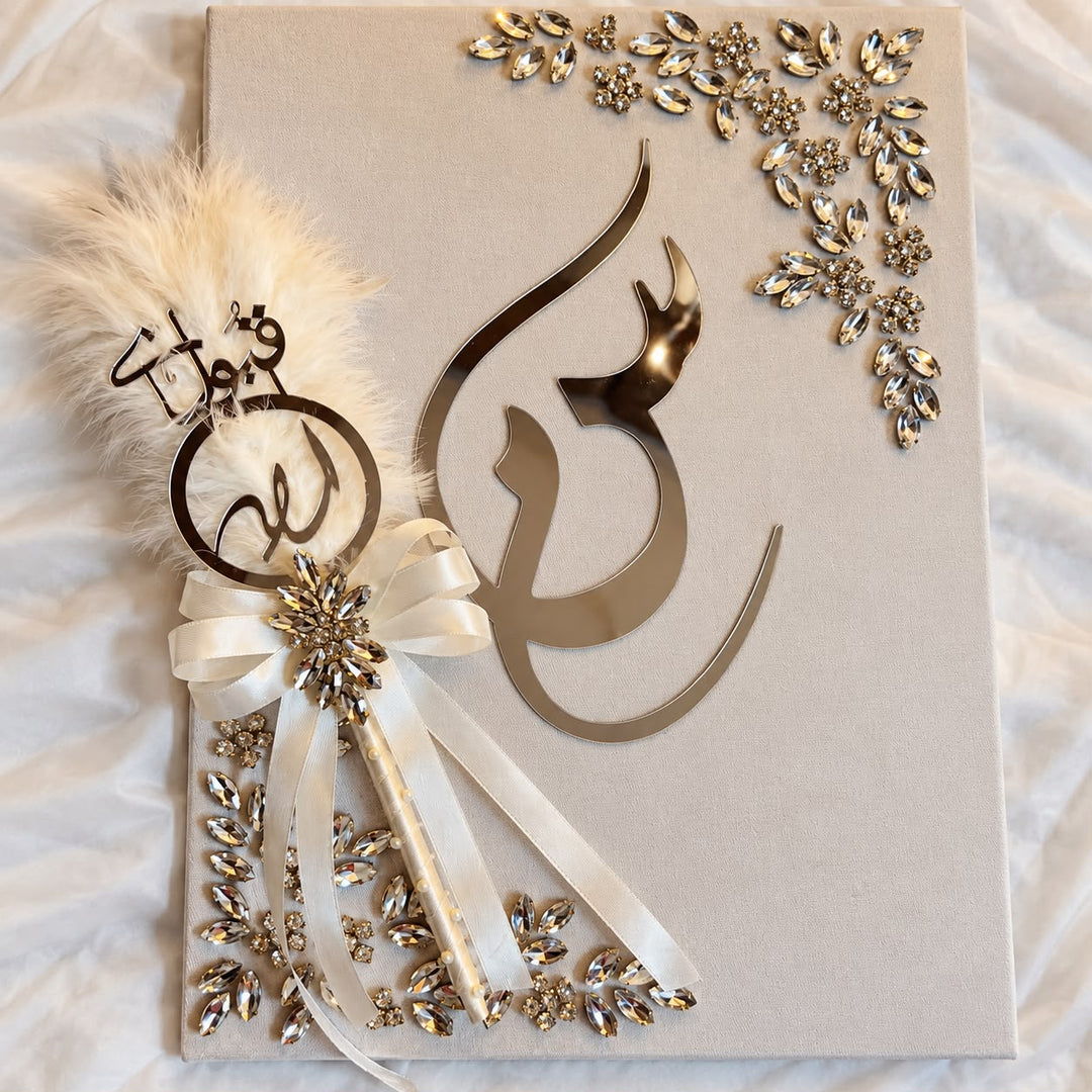 Luxury beige calligraphy keepsake with gold-tone Arabic lettering, crystal floral embellishments, and an ivory satin ribbon.