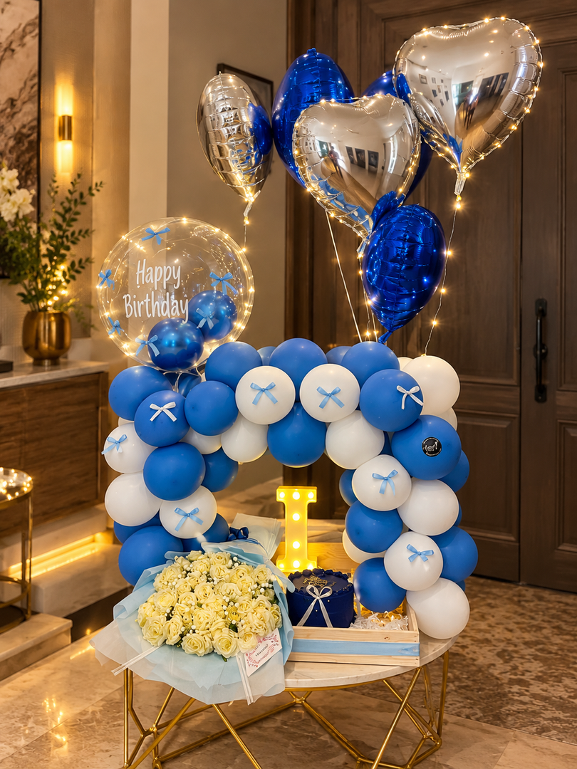 Sapphire Birthday Luxe with blue and white balloon arch, silver heart balloons and white flower bouquet