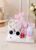 Load image into Gallery viewer, Premium baby girl gift box with baby shoes, white outfit, flower sunglasses, colorful washcloths, hair accessories, and elegant pink ribbon in a transparent keepsake box.