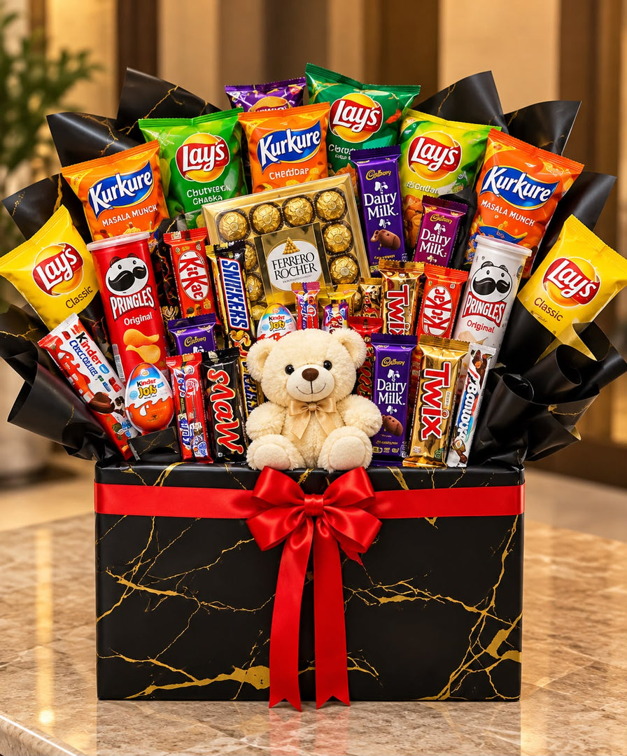 Choco Crunch Hamper with assorted chocolates, snack packets, a teddy bear and a red ribbon on a black gift box.