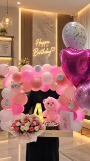 Roselle Blush elegant birthday setup with pink balloons, roses, teddy bear and cake