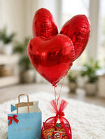 Load image into Gallery viewer, Three shiny red heart-shaped foil balloons with red ribbons tied to a birthday snack hamper.
