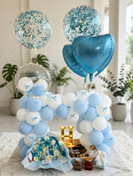 Load image into Gallery viewer, Blue roses and white flowers in pale blue wrapping beside a birthday cake and glowing gold-coloured letter H.