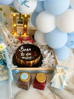 Load image into Gallery viewer, Round birthday cake with a dark topping, white piped lettering, and patterned sides, nestled in a wooden gift tray.